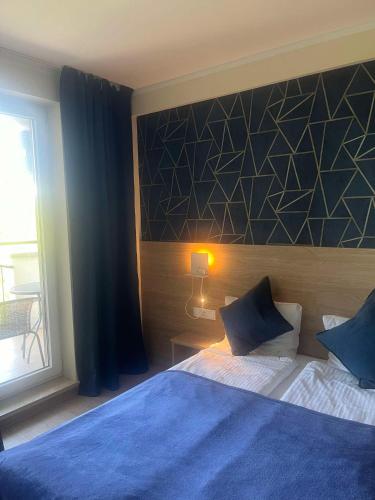 a bedroom with a blue bed and a window at Apartament 505 in Mielno