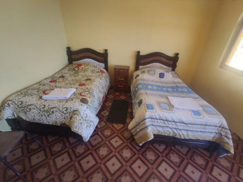 two beds sitting next to each other in a bedroom at Hostal Mirador del Sol in Comunidad Challapampa
