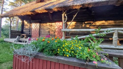a log cabin with flowers in front of it at Käbliku Puhkemajad in Kanepi