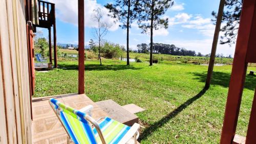 a chair sitting on a porch with a view of a field at Chalézinho Bons Ventos Campestre no Sitio com Churrasqueira WI-FI a 6km da Estrada do Mar 7km Parque de Rodeio II 8,1Km Prefeitura II 7,2Km UFRGS Litoral II Taxi Fácil II Tranquilidade 12km Praias Tramandai in Osório