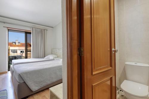 a bathroom with a bed and a toilet in a room at Hotel Nova Cidade in Amadora