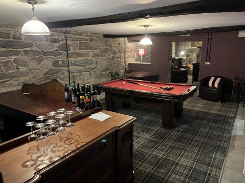 a bar with a pool table and wine glasses at Maes Y Neuadd Country House in Talsarnau