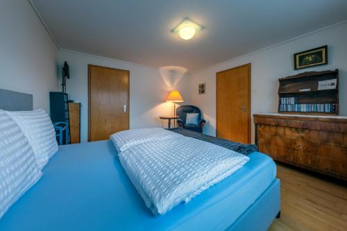 a bedroom with a blue bed and a wooden dresser at Blattenheimat - im traditionellen Appenzeller Haus in Appenzell