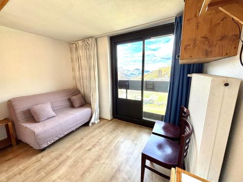 un salon avec un canapé et une grande fenêtre dans l'établissement Studio économique 2 pers. avec balcon aux Menuires, animaux admis - FR-1-452-160, aux Menuires