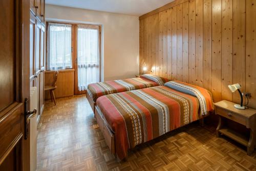 a bedroom with two beds and a wooden wall at Villa Chiappuzza - Stayincortina in San Vito di Cadore