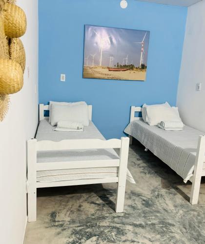 two beds in a room with a picture on the wall at Pousada Marina Pecém in São Gonçalo do Amarante