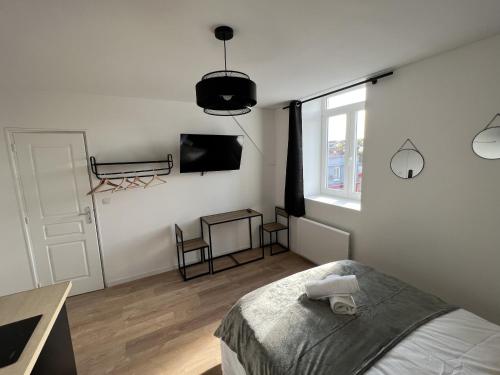 a white bedroom with a bed and a television at Le Cosy, 2P Centre-ville in Liévin
