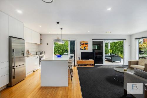 a kitchen and living room with a white counter top at Stylish Northcote Point Bungalow in Auckland