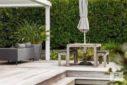 a patio with an umbrella and a table and chairs at Stylish Northcote Point Bungalow in Auckland