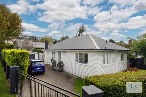 a white house with a car parked in a driveway at Stylish Northcote Point Bungalow in Auckland
