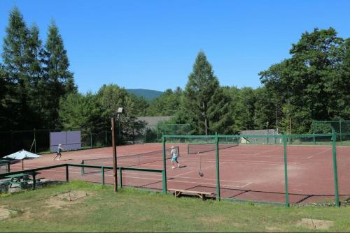 three people playing tennis on a tennis court at Cold Spring Plymouth Resort in Ashland