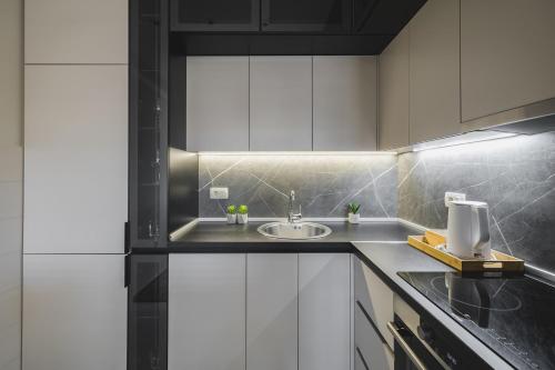 a kitchen with white cabinets and a sink at Harmony Apartments in Podgorica