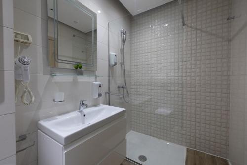 a white bathroom with a sink and a shower at Harmony Apartments in Podgorica