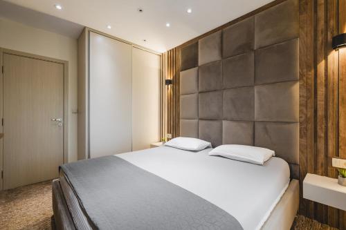 a bedroom with a large white bed and a wall at Harmony Apartments in Podgorica