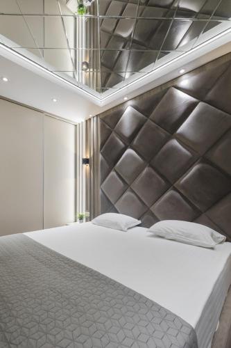 a bedroom with a large bed with a silver headboard at Harmony Apartments in Podgorica