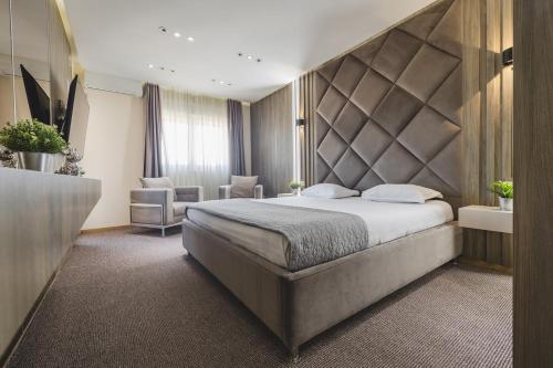 a bedroom with a large bed with a padded headboard at Harmony Apartments in Podgorica