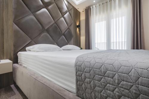 a bedroom with a large bed with a large headboard at Harmony Apartments in Podgorica