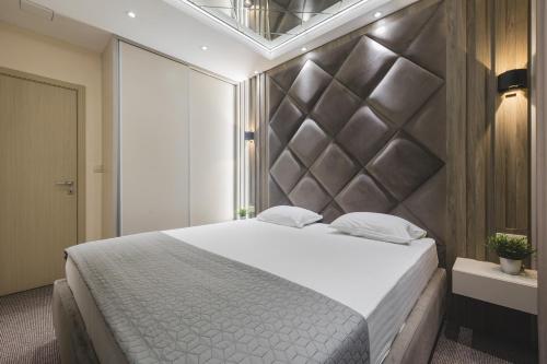 a bedroom with a large bed with a large headboard at Harmony Apartments in Podgorica