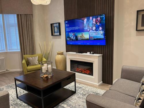 a living room with a fireplace and a flat screen tv at Luxury 2 Bedroom Cottage in West Calder