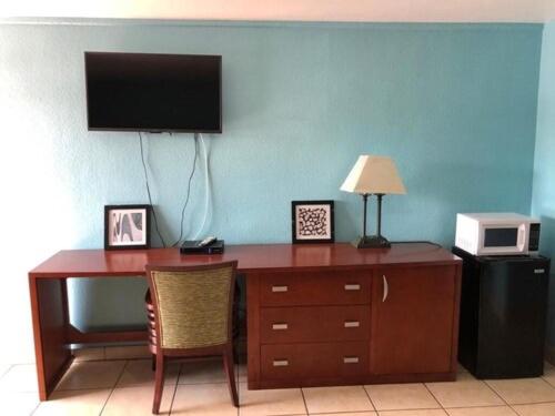 a desk with a television and a desk with a chair at Economy Suites in Winter Haven