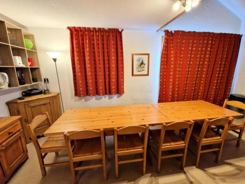 une table à manger en bois avec des chaises et des rideaux rouges dans l'établissement Les Chalets D'arrondaz - Joli duplex 10/12 personnes MAE-2892, à Modane