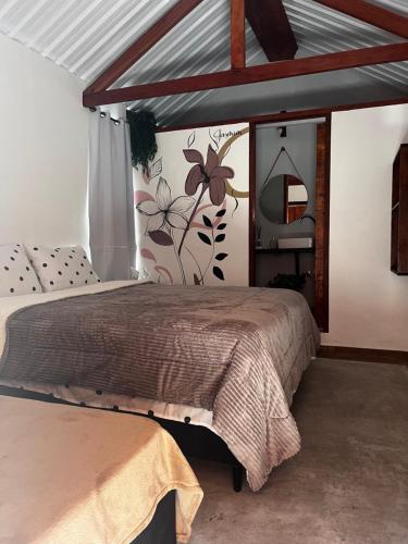 a bedroom with a bed and a wall with flowers at Chales em Salesopolis - Recanto da Barra in Salesópolis