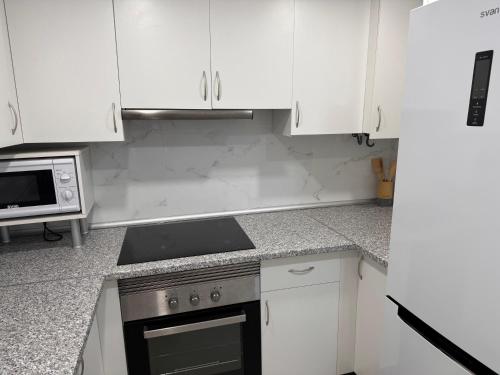 a kitchen with white cabinets and a stove and a microwave at Loft muy céntrico a 250m del mar in Vinaròs