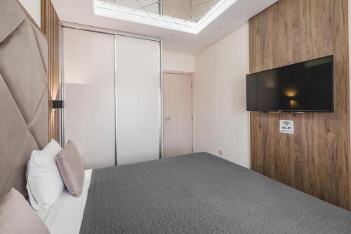 a bedroom with a bed with a tv on the wall at Harmony Apartments in Podgorica
