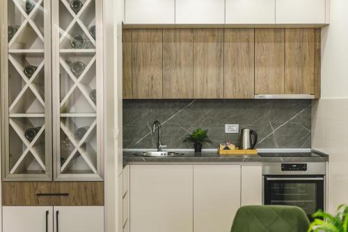 a kitchen with white cabinets and a sink and a wine cellar at Harmony Apartments in Podgorica