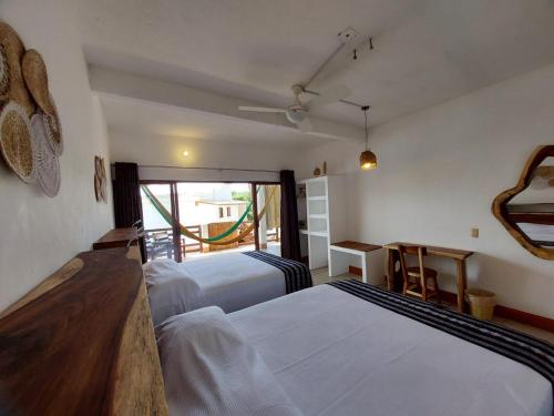 a bedroom with two beds and a table and a window at Posada Ziga Playa in Mazunte