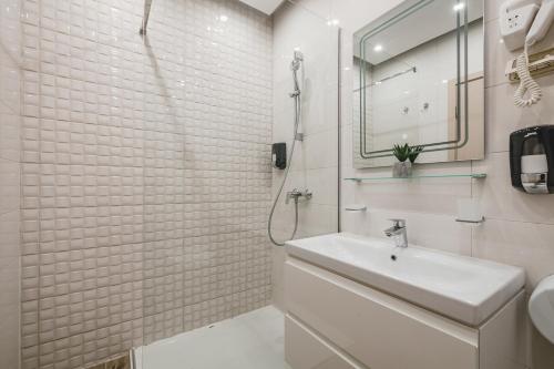 a white bathroom with a sink and a shower at Harmony Apartments in Podgorica