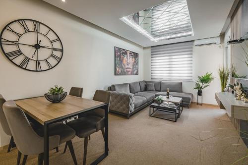 a living room with a couch and a clock on the wall at Harmony Apartments in Podgorica