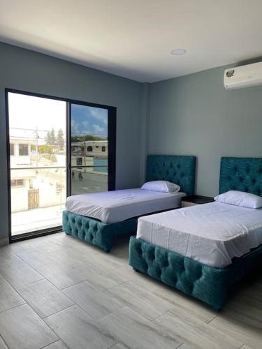 Un dormitorio con dos camas y una gran ventana. en Casa hermosa con piscina, en Salinas