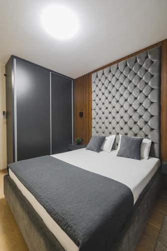a bedroom with a large bed with a large headboard at Harmony Apartments in Podgorica