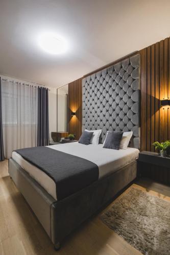 a bedroom with a large bed with a large headboard at Harmony Apartments in Podgorica