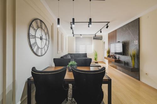 a dining room with a table and chairs and a clock at Harmony Apartments in Podgorica
