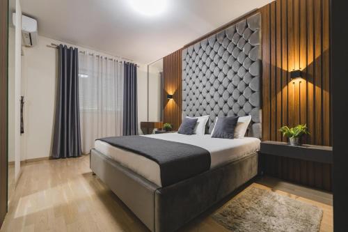 a bedroom with a large bed with a large headboard at Harmony Apartments in Podgorica