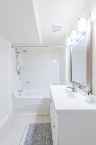 a white bathroom with a sink and a mirror at UofC-SAIT-Banff Trail-Suite A&B in Calgary