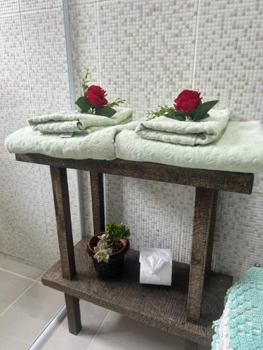 a bathroom table with towels and flowers on it at Casa do Aconchego in Campos do Jordão