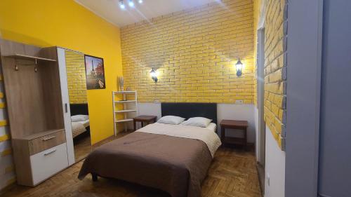 a bedroom with a bed and a yellow brick wall at Lorf Hostel&Coffee in Kraków