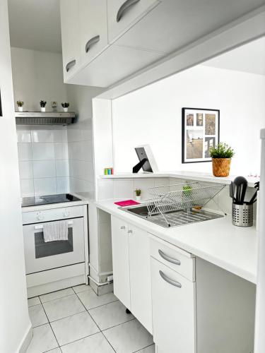 - une cuisine blanche avec des placards blancs et une cuisinière dans l'établissement Appartement F3 avec Projecteur à 100m du Métro!, à Saint-Ouen