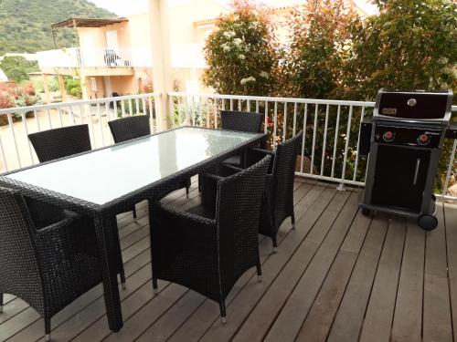 une table et des chaises sur une terrasse avec un grill dans l'établissement Résidence Santa Giulia Park 1 avec piscine à proximité des plages, à Porto-Vecchio