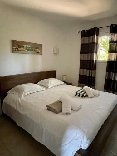 une chambre avec un grand lit blanc avec des serviettes dessus dans l'établissement Résidence Santa Giulia Park 1 avec piscine à proximité des plages, à Porto-Vecchio