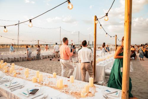 a group of people standing around tables on the beach at Blu Suite Resort in Bellaria-Igea Marina