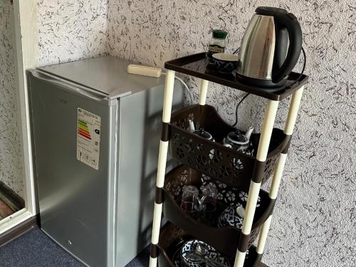 a shelf next to a refrigerator with a tea kettle on it at Мини Отель in Fergana