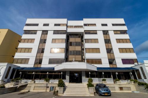 a building with a car parked in front of it at Hotel Axis Inn By GEH Suites in Santa Marta