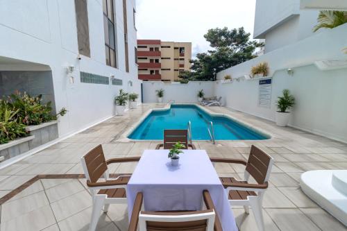 a patio with a table and chairs and a swimming pool at Hotel Axis Inn By GEH Suites in Santa Marta