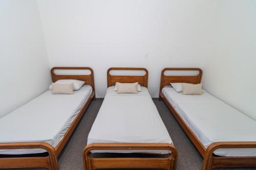 a group of three beds in a room at Hotel Axis Inn By GEH Suites in Santa Marta