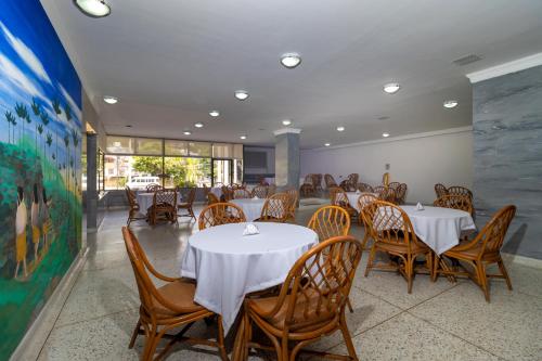a dining room with white tables and wooden chairs at Hotel Axis Inn By GEH Suites in Santa Marta