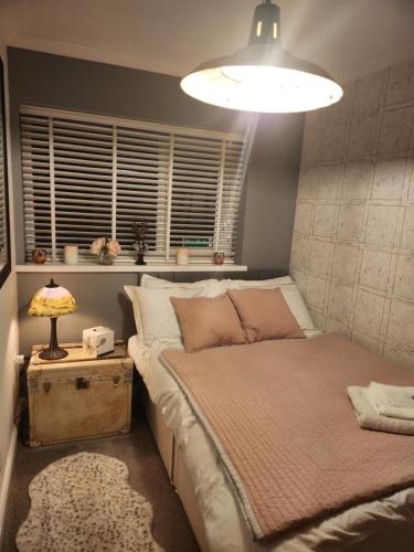 a bedroom with a bed and a lamp and a window at The lodge in Blackwood